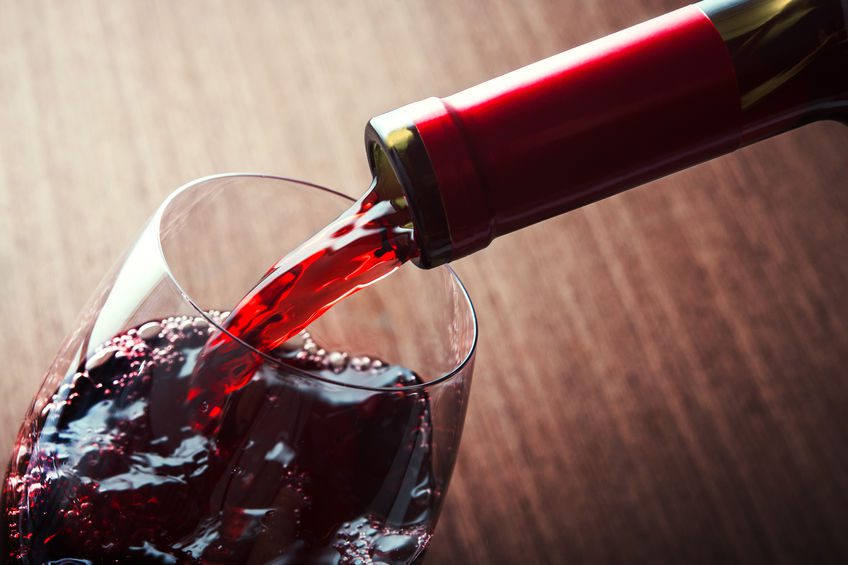 A close up of red wine being poured into a wine glass